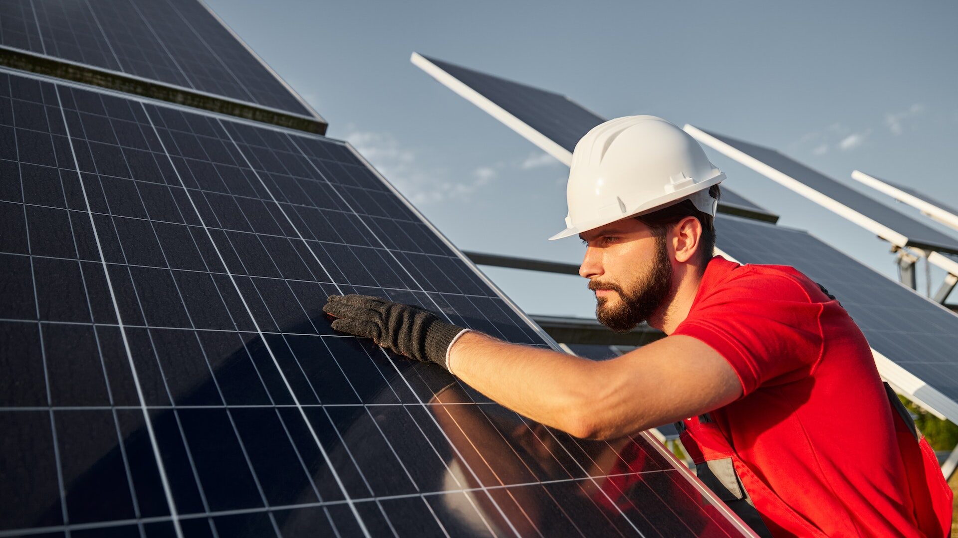 Engineer in workwear and hardhat cleaning solar panel